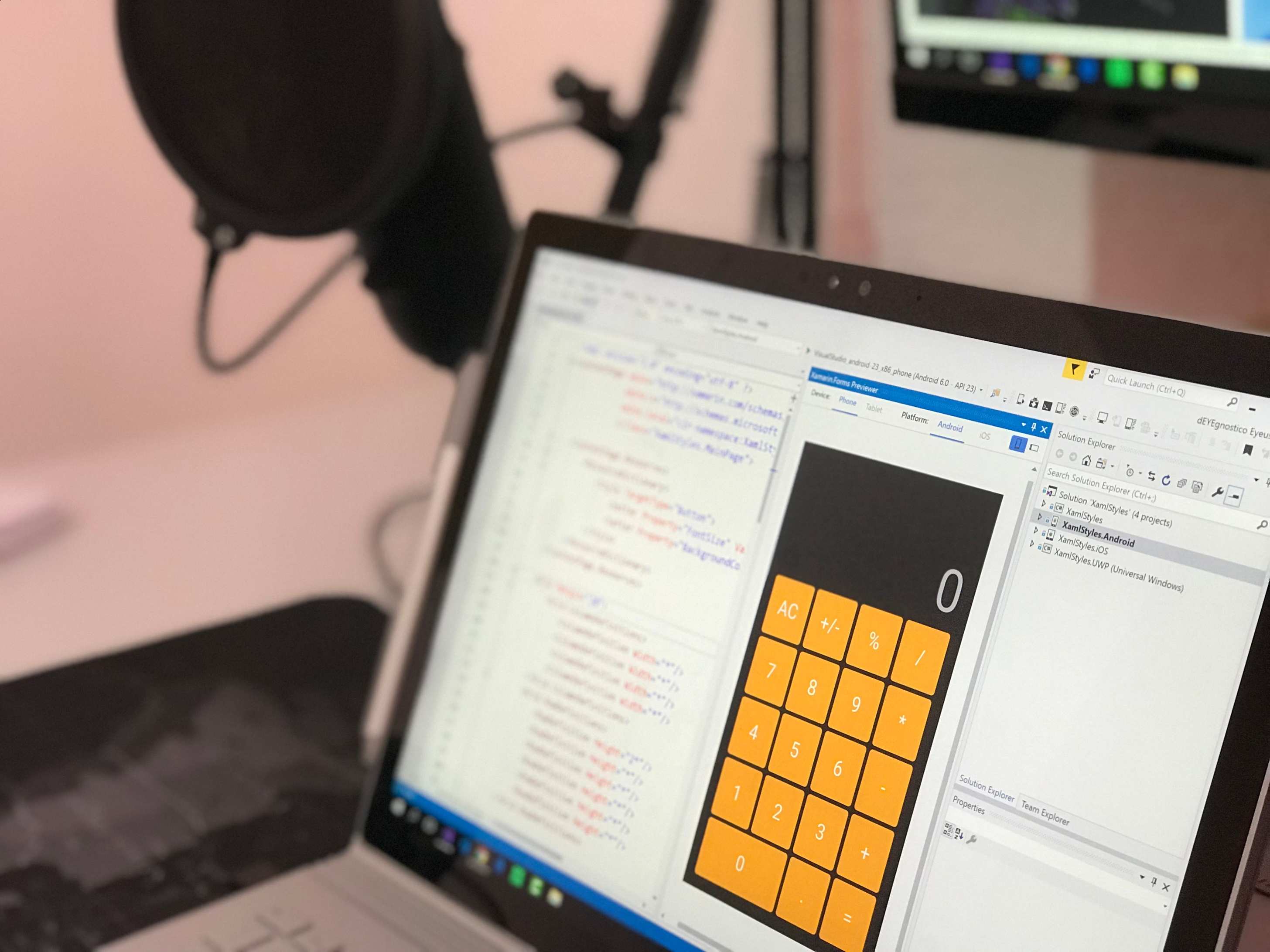 Close-up of a laptop displaying code and a calculator app in a modern workspace